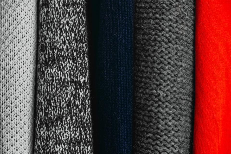 Row of folded knit sweaters in grey, navy and red