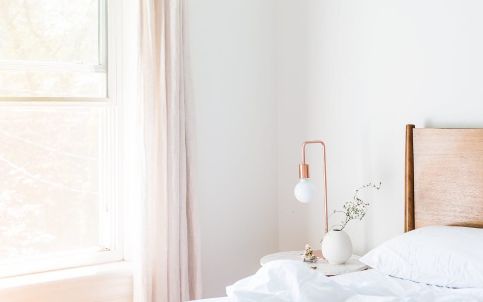 Bright bedroom with white bedding and a small bedside lamp