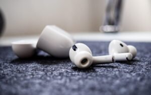 Pair of white wireless earbuds lying beside their charging case