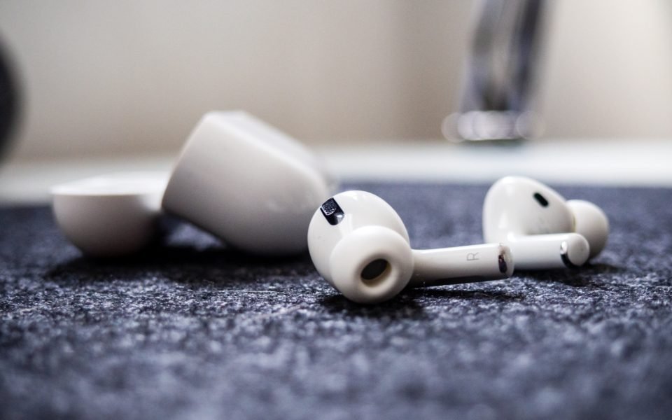 Pair of white wireless earbuds lying beside their charging case