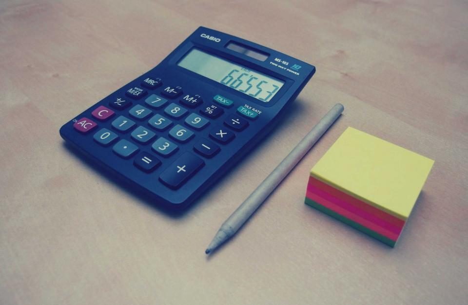 Blue calculator, pencil and sticky notes on a desk