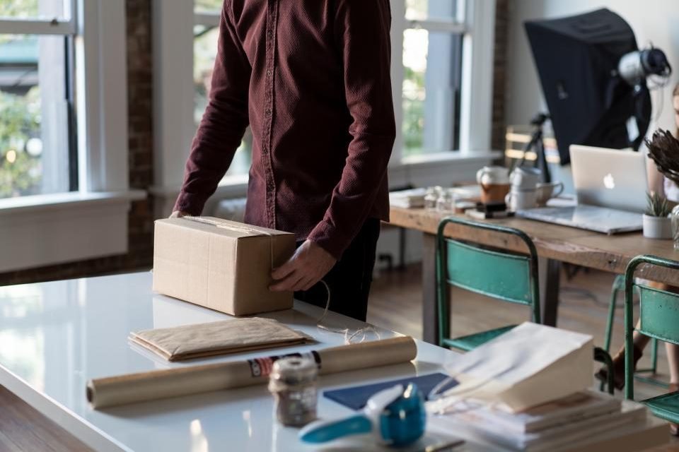 Person packing a cardboard parcel on a work table