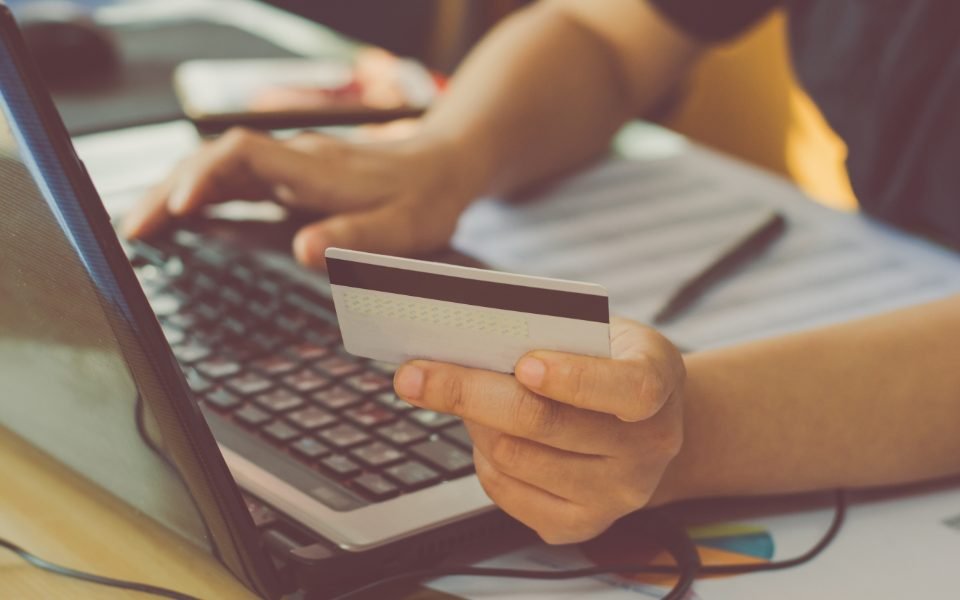 Hands holding a payment card over a laptop keyboard