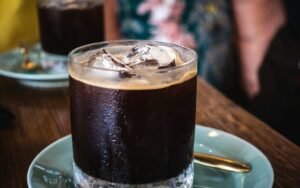 Glass of iced black coffee on a saucer
