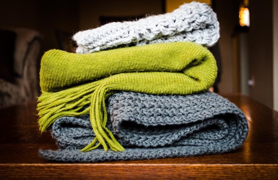 Stack of folded knitted blankets in green and grey