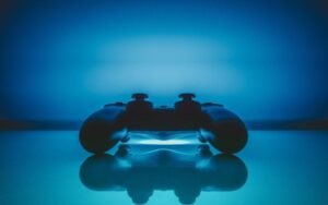 Game controller lit in blue, reflected on a glossy surface