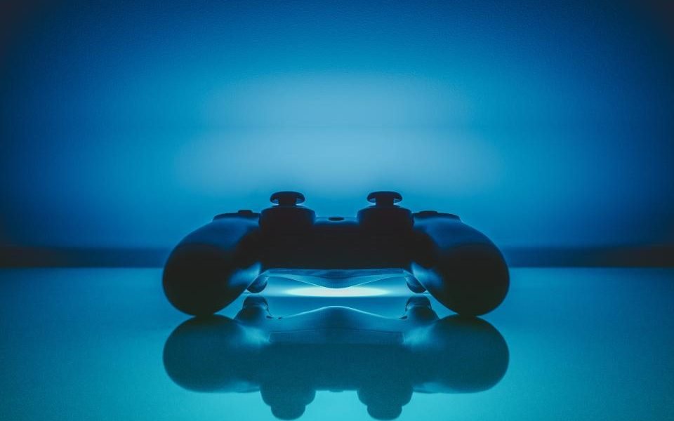 Game controller lit in blue, reflected on a glossy surface