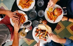 Friends sharing burgers, fries and salads at a restaurant table, seen from above