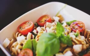 Bowl of pasta with cherry tomatoes, cheese and fresh basil