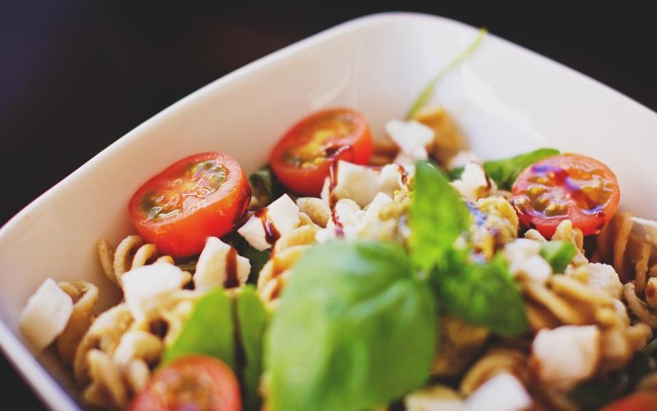 Bowl of pasta with cherry tomatoes, cheese and fresh basil