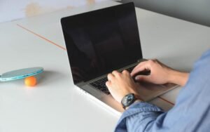 Hands typing on a laptop at a white desk