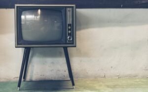 Vintage television on thin legs against a whitewashed wall