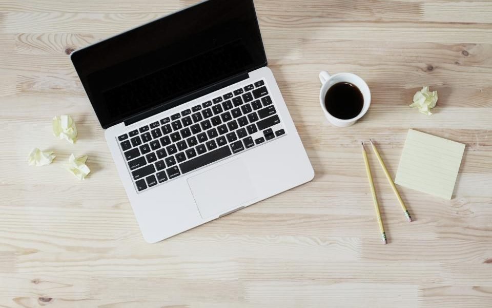 Laptop, coffee cup and pencils on a light wooden desk