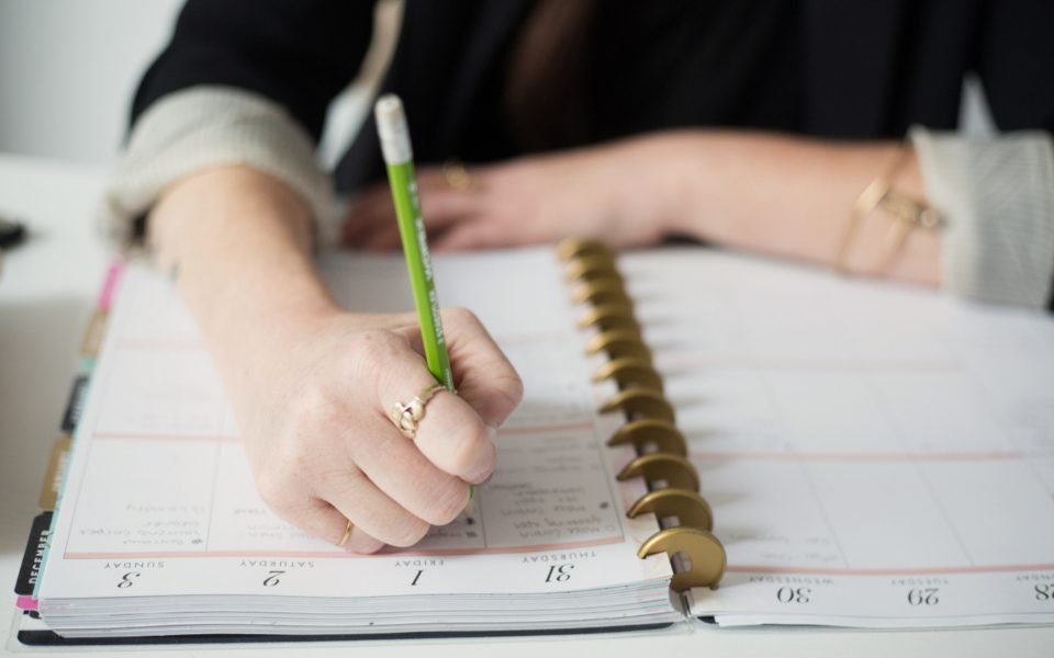 Hand writing a weekly plan in a ring-bound planner