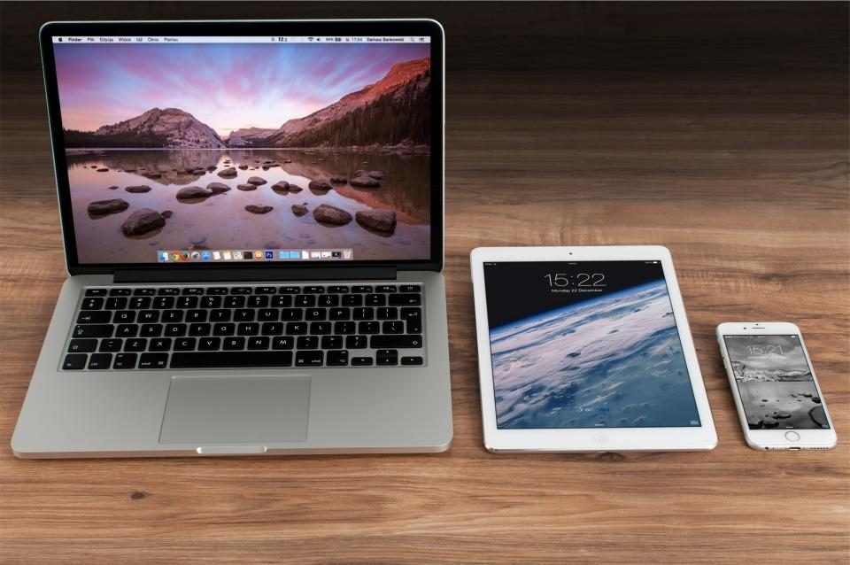 Laptop, tablet and smartphone side by side on a wooden desk