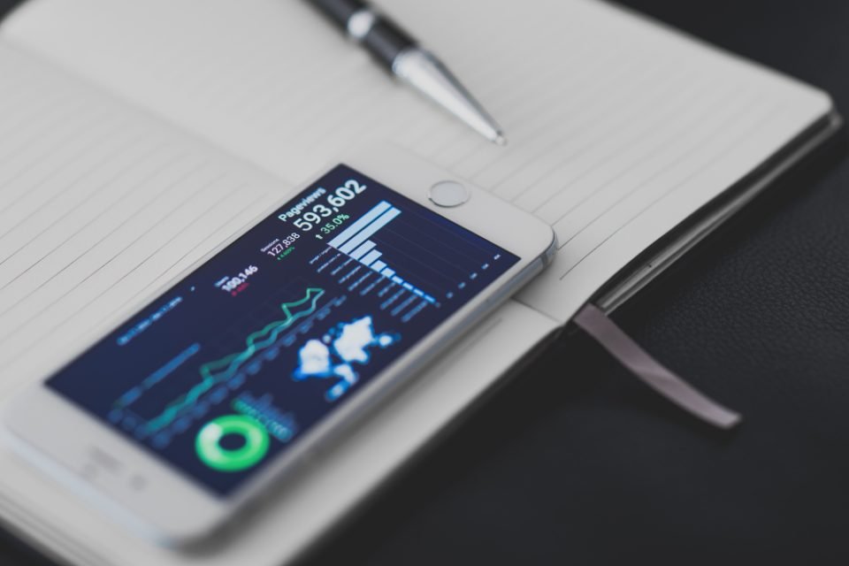 Smartphone showing charts, lying on an open notebook