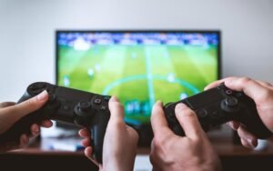 Two people holding game controllers in front of a TV showing a football game