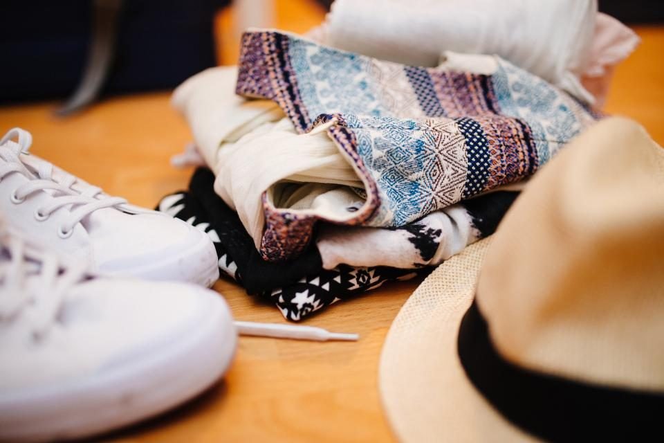 Folded patterned clothes, a hat and white sneakers on a table