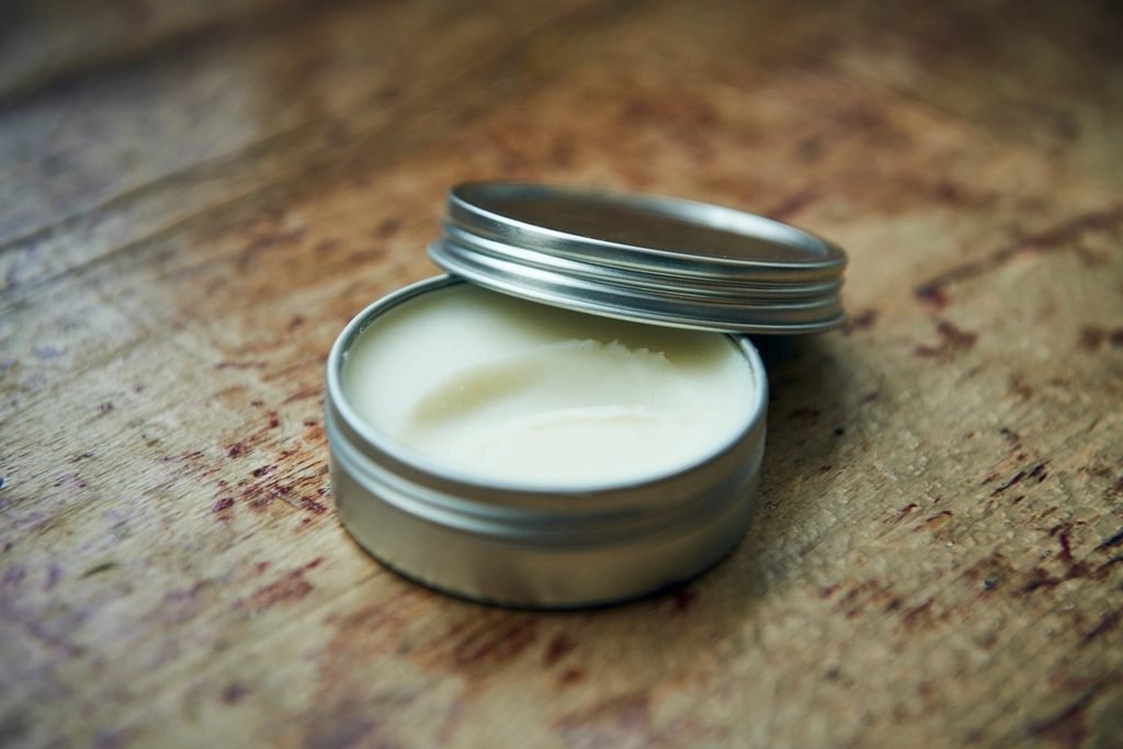 Open metal tin of balm on a wooden table
