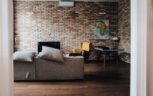 Compact living room with a brick wall, grey sofa and small dining table