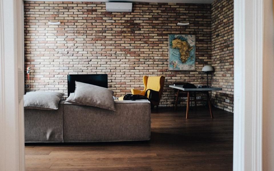 Compact living room with a brick wall, grey sofa and small dining table