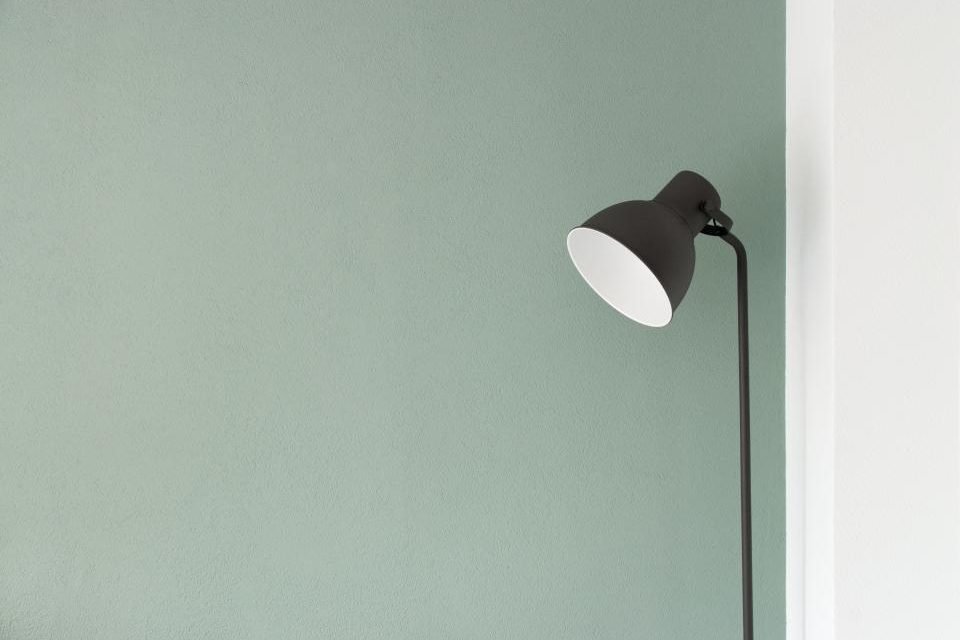 Black floor lamp against a pale green wall