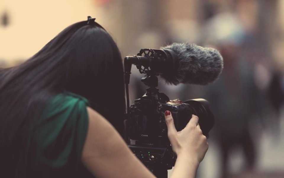 Person filming with a video camera fitted with a microphone