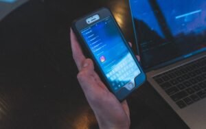 Hand holding a smartphone in front of a laptop