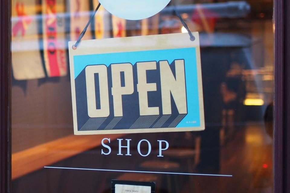 Blue OPEN shop sign hanging in a store window