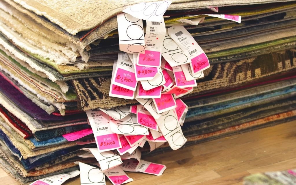 Stack of rugs with pink price tags hanging from the edges