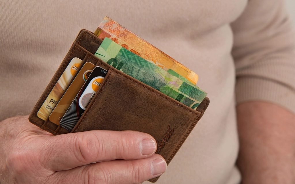 Hand holding a leather wallet with cards and banknotes