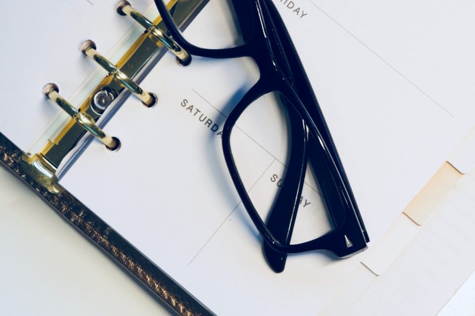 Open weekly planner with a pair of glasses resting on it