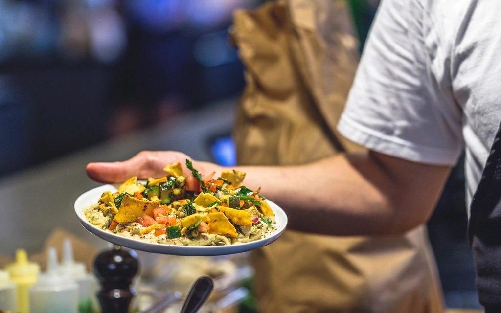 Server carrying a plate of food through a busy restaurant