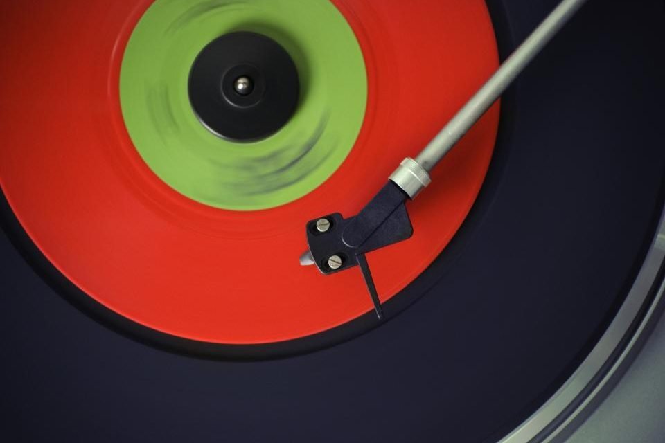 Red and green vinyl record spinning under a turntable tonearm