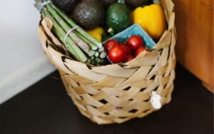 Wicker basket filled with fresh vegetables and avocados