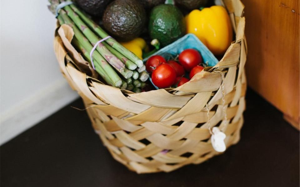 Wicker basket filled with fresh vegetables and avocados